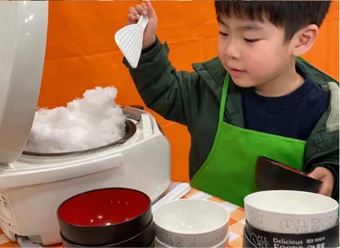エプロンをつけて、わたあめ機からわたあめを取る子ども