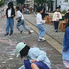 氷見駅前の道路にチョークで絵を描いて遊ぶ子どもたち
